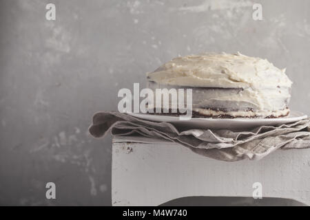 Eine ganze (Karotte) Kuchen mit Weiß Creme auf grauem Hintergrund. Festliches dessert Konzept. Stockfoto