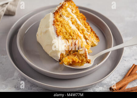 Stück Karotte hausgemachte Kuchen mit Weiß Creme auf grauem Hintergrund. Festliches dessert Konzept. Stockfoto