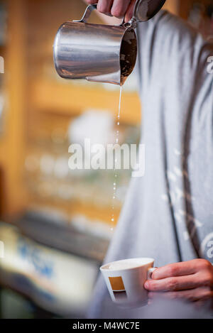 Gießen Milch in einem Espresso Kaffee Tasse Stockfoto