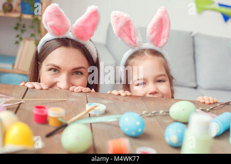 Mutter und Tochter zusammen im bunny Ohren zu Hause Ostern versteckt unter der Tabelle Stockfoto