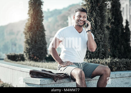 Fröhlicher schöner Mann in einem Telefongespräch Stockfoto