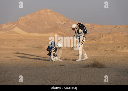 Analoge Astronauten, verkleidet in einem speziellen Raumanzügen, umherwandern das Gelände der Mars-ähnlichen Forschungseinrichtung für den D-MARS (Desert Mars Analog Ramon Station), eine einzigartige Initiative für einen Lebensraum für Planetenforschung, der in einem isolierten Wüstengebiet im Ramon Crater in der Negev-Wüste gebaut wurde. Die Analogastronauten leben in der Forschungseinrichtung und können den Lebensraum nur in Raumanzügen verlassen. Während der Isolation führt das Team eine Reihe von wissenschaftlichen und technologischen Experimenten durch, in der Hoffnung, die Grundlagen für zukünftige bemannte Missionen zum Mars zu schaffen. Stockfoto