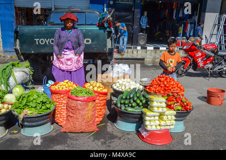 Einer guatemaltekischen Frau in traditioneller Kleidung und ein junge Gemüse verkaufen Auf einem Straßenmarkt. Stockfoto