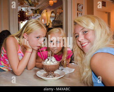 Horizontales Bild von drei Blonden und blauäugigen Mädchen trinken einen gefrorenen Heiße Schokolade Dessert. Stockfoto