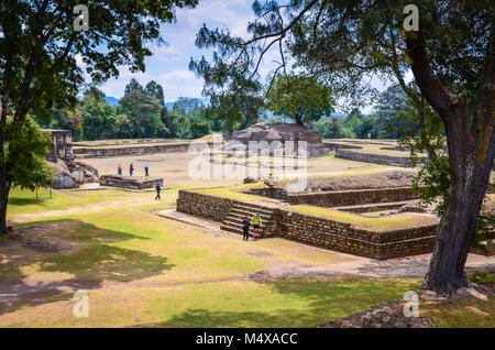 Ruinen von Iximche von riesigen Eichen eingerahmt. Iximche ist eine kolumbianische Mesoamerican archäologische Stätte im westlichen Hochland von Guatemala mit p Stockfoto