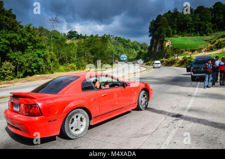 Eine Mutter und Kind sitzen in einem geparkten roten Sportwagen auf Pan-American Highway in der Nähe von Guatemala City, Guatemala. Stockfoto