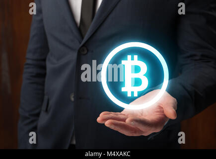 Geschäftsmann holding Bitcoin virtuelle Zeichen auf seiner Hand Stockfoto