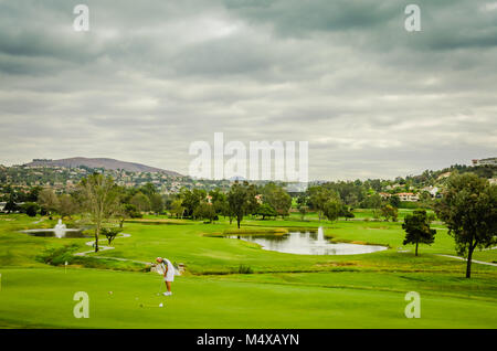 Ein Golfspieler setzt auf dem grünen Golf Kurs trotz grauer Wolken und bevorstehende Regen. Stockfoto