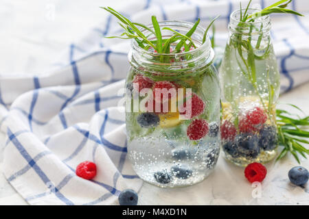 Beeren und Estragon in Jar mit glitzerndem Eis Wasser. Stockfoto