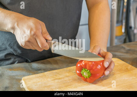 Koch schneiden Red Paprika auf Holz Breite Stockfoto