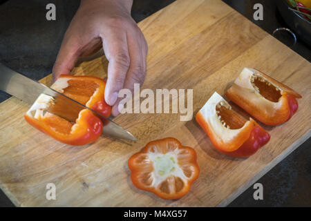 Koch schneiden Red Paprika auf Holz Breite Stockfoto