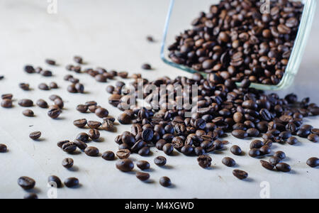 Kaffeebohnen auf dem Tisch verstreut, upside-down Glasschale, Stockfoto