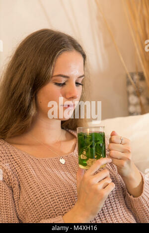 Junge Frau genießt eine Tasse Tee, frischen Pfefferminztee, mit Minze, Stockfoto