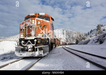 Ein BNSF train Kommen hinunter die Spuren im Schnee An einem kalten, hellen, sonnigen Tag. Bei Bearmouth, westlich von Drummond, Montana in Granit County. Stockfoto