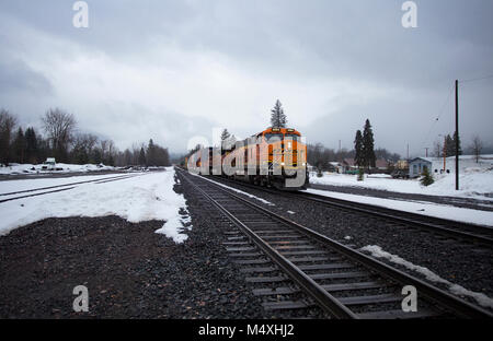 Ein BNSF train unten kommen die Tracks in die Stadt Troja, Montana Stockfoto