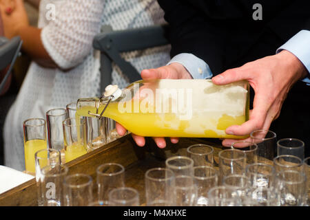 Nahaufnahme von einem Kellner mit Limoncello in Gläsern auf einer Party Stockfoto