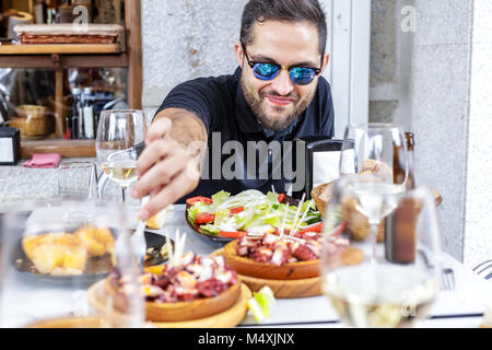 Junger Mann essen Pulpo a la Gallega mit Kartoffeln. Galizische octopus Gerichte. Bekannte Gerichte aus Galizien, Spanien. Stockfoto