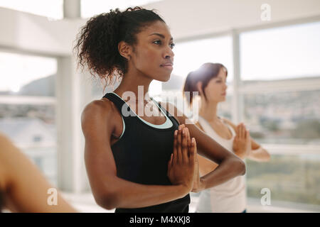 Frauen Yoga zusammen, stehend mit Händen in Namaste Geste. Frauen stehen im Yoga pose im Fitnessstudio. Stockfoto