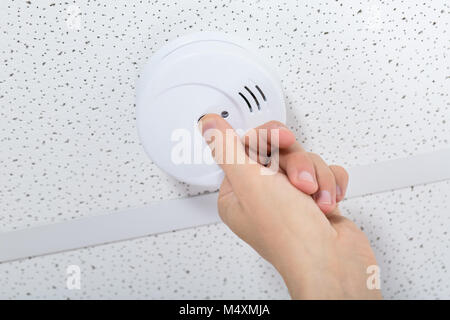 Low Angle View eines Menschen Hand Installation Rauchmelder an der Decke Wand zu Hause Stockfoto