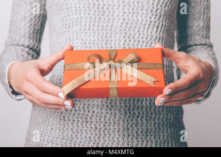 Geschenkverpackung Geschenkpapier in Rot mit goldenen Band in weibliche Hände close-up Stockfoto