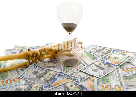 Skelett Finger holding Sand - Glas auf Dollar platziert. Konzept der Zeit - Geld und Tod. Stockfoto