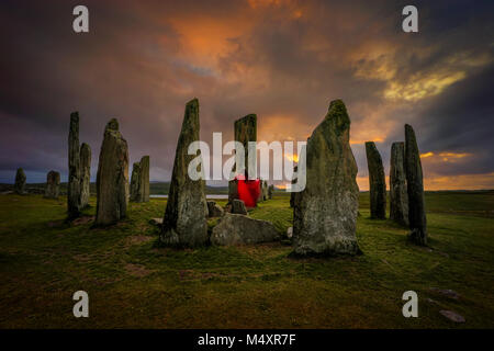 Die Frau im roten Kleid an Callanish stones im Abendlicht, Lewis, Schottland Stockfoto