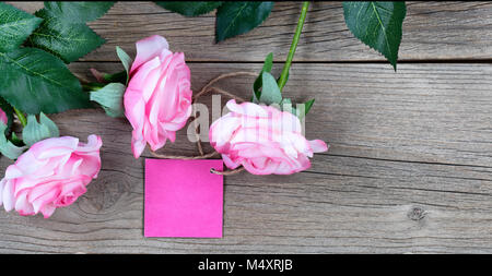 Rosa Rosen mit Geschenkanhänger auf verwitterte Holzbretter Stockfoto