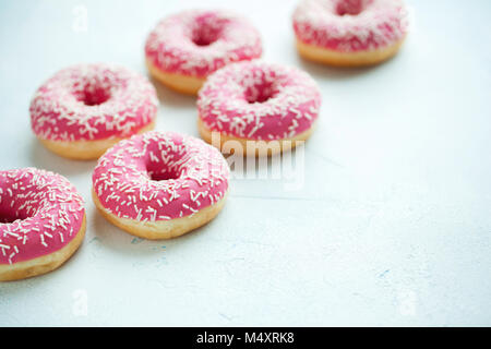 Donut. Süße Puderzucker essen. Dessert bunte Snack. Behandeln von leckeren Gebäck Frühstück. Bäckerei Kuchen. Donut mit Zuckerguss. Gebackene ungesunde Runde auf einem blauen Hintergrund. mit Platz kopieren Stockfoto