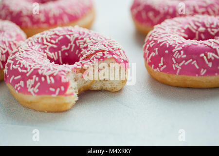 Gebissen Donut. Süße Puderzucker essen. Dessert bunte Snack. Glasierte Streuseln. Behandeln von leckeren Gebäck Frühstück. Bäckerei Kuchen. Donut mit Zuckerguss. Gebackene ungesunde Runde Stockfoto