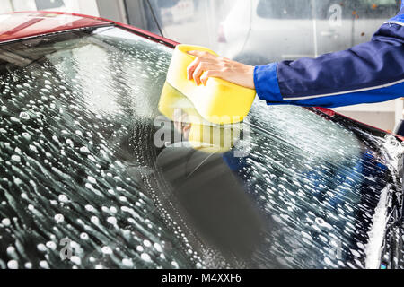 Person's Hand Reinigung Auto Windschutzscheibe mit Schwamm an der Service-Einheit Stockfoto