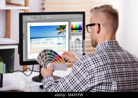 Einen männlichen Designer über Computer, während Sie Farbe in seiner Hand Muster Stockfoto
