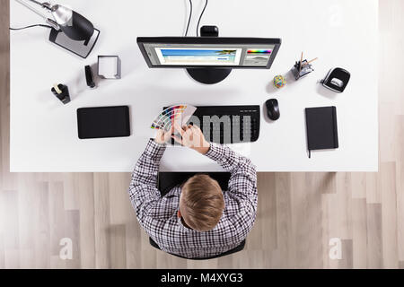 Hohe Betrachtungswinkel eines männlichen Designer Holding Farbmuster und über Computer im Büro Stockfoto