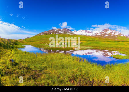 Blauer See Wasser reflektiert die verschneite Hügel in Island Stockfoto