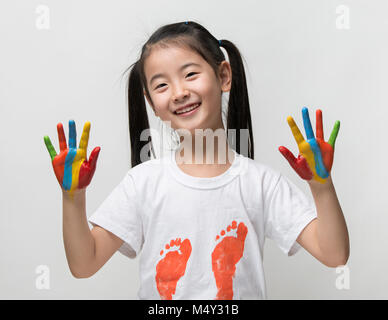 Kleine Asiatin mit Händen in bunten Farben lackiert Stockfoto