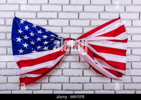 Amerikanische Flagge, in einem Knoten gebunden, auf einer weißen Wand. Visuelles Konzept der Vorbereitung für Tag der Unabhängigkeit. Am 4. Juli patriotischen consept. Stockfoto