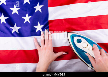 Frau Hände drücken der amerikanischen Flagge mit einem Bügeleisen. Visuelles Konzept der Vorbereitung für Tag der Unabhängigkeit. Am 4. Juli patriotischen consept. Stockfoto