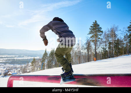 Zurück Porträt der jungen snowboarder Durchführung stunt Hineinrutschen Metallgeländer im Sonnenlicht am Ski Resort anzeigen, kopieren Raum Stockfoto