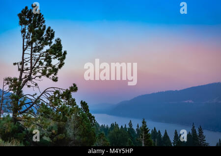 Blick auf den Lake Tahoe von Barsch über Bäumen auf einem dunkelrosa Sonnenuntergang am Abend. Stockfoto