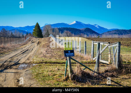 Kein Übertreten Zeichen auf einem hölzernen Pfosten am Eingang eine unbefestigte Straße, die zu Schnee-bedeckten Adirondack Mountains. Stockfoto