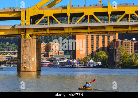 Ein einsamer Mann Zeilen ein Kajak auf dem Ohio River unter der gelben Brücke in Pittsburgh, Pennsylvania. Stockfoto