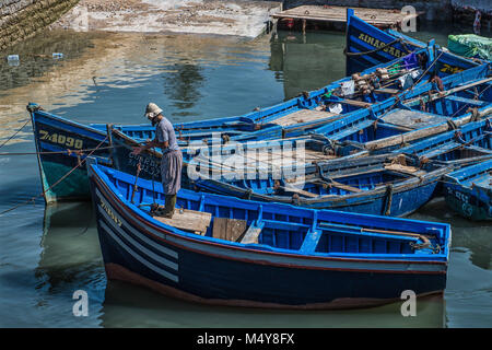 Ein einheimischer Fischer arbeitet auf der berühmten blauen Boote im Hafen von Essaouira. Die Boote und Wasser sind eine leuchtende blaue Farbe. Stockfoto