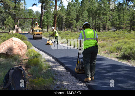 Arbeitnehmer Asphalt mit Pflastern Maschinen. Zwischen 10. August bis 10. September 2016 die Greenway Trail zwischen dem IMAX Theater Parkplatz in Tusayan und Centre Road im Grand Canyon National Park wird geschlossen werden, während der Grand Canyon Trail crew installiert Asphalt. Der Teil der Trail im Norden von der Mitte der Straße nicht beeinträchtigt werden. Während die trail Schließung in Kraft ist, Radfahrer und Wanderer können die Tusayan Shuttle (lila Route), die mit Fahrradträger Racks ausgestattet ist. Der Shuttle verbindet Tusayan mit den South Rim Visitor Zentrums, jeweils eine 20-minütige Fahrt. Die Absicht dieses Projektes Stockfoto