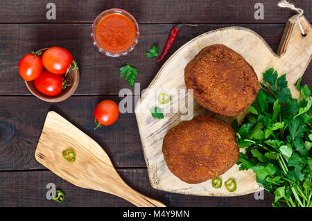 Große saftige Schnitzel gefüllt mit gekochtem Ei auf einem Schneidebrett auf einem dunklen Hintergrund. Schottische Schnitzel. Die Ansicht von oben Stockfoto