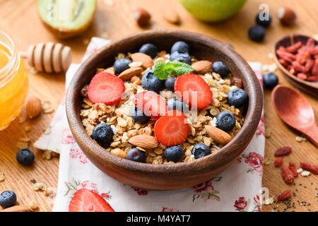 Müsli Schale mit frischen Erdbeeren, Blaubeeren, Getrocknete Goji Beeren und Mandeln auf Holztisch. Konzept der gesunden Lebensweise, gesunde Ernährung, dieti Stockfoto