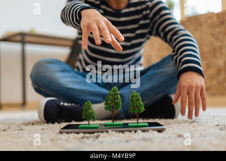 Teenager in Baum Miniaturen auf seinem Tablet Stockfoto