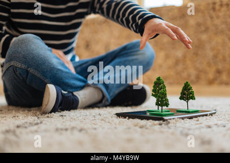 Junge in Baum Miniaturen auf seinem Tablet Stockfoto