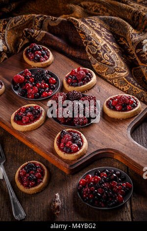 Köstlichen Beerenfrüchten mini Torten (Törtchen) auf Holz- Hintergrund Stockfoto