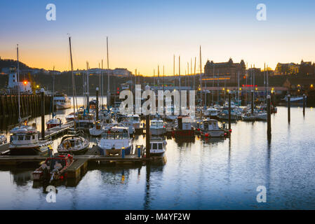 Scarborough, Blick in der Dämmerung auf den Hafen und Skyline von Scarborough aus dem Norden von South Bay Beach, North Yorkshire gesehen. Stockfoto