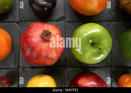 Eine Vielzahl von bunten Früchte auf schwarze Quadrate aus Schiefer Stein Stockfoto