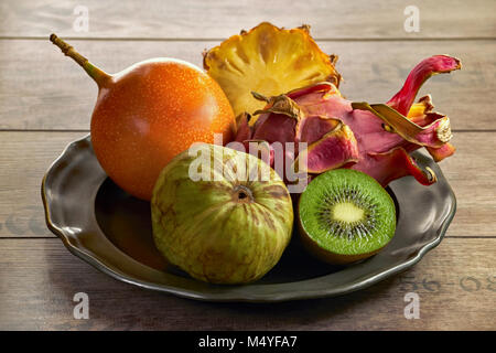 Eine Platte mit exotischen Früchten - Cherimoya, Kiwi, Pitahaya, Granadilla, Ananas Stockfoto